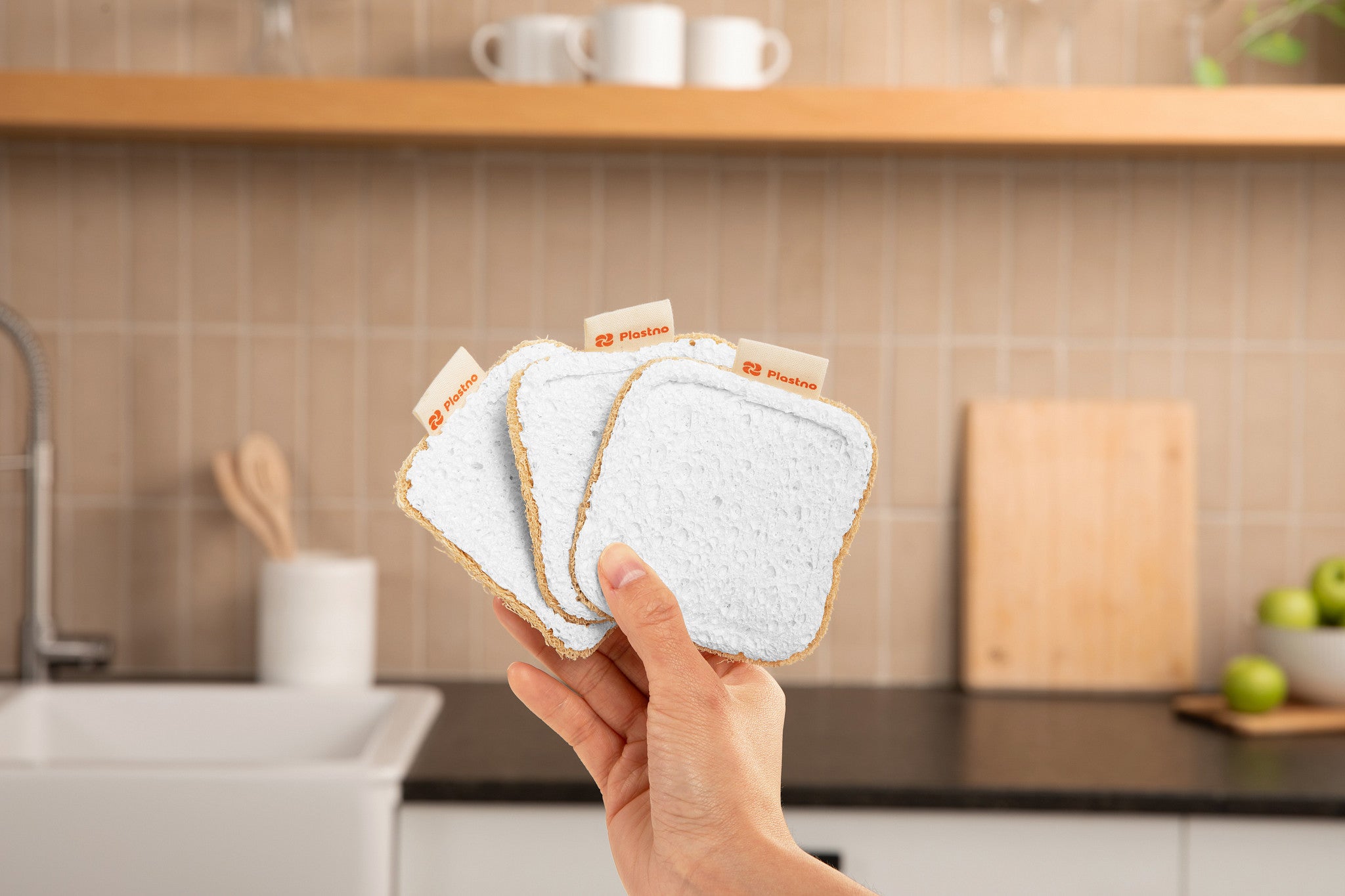Hand holding Plastno biodegradable cellulose sponges, plastic-free dish sponges for everyday kitchen cleaning