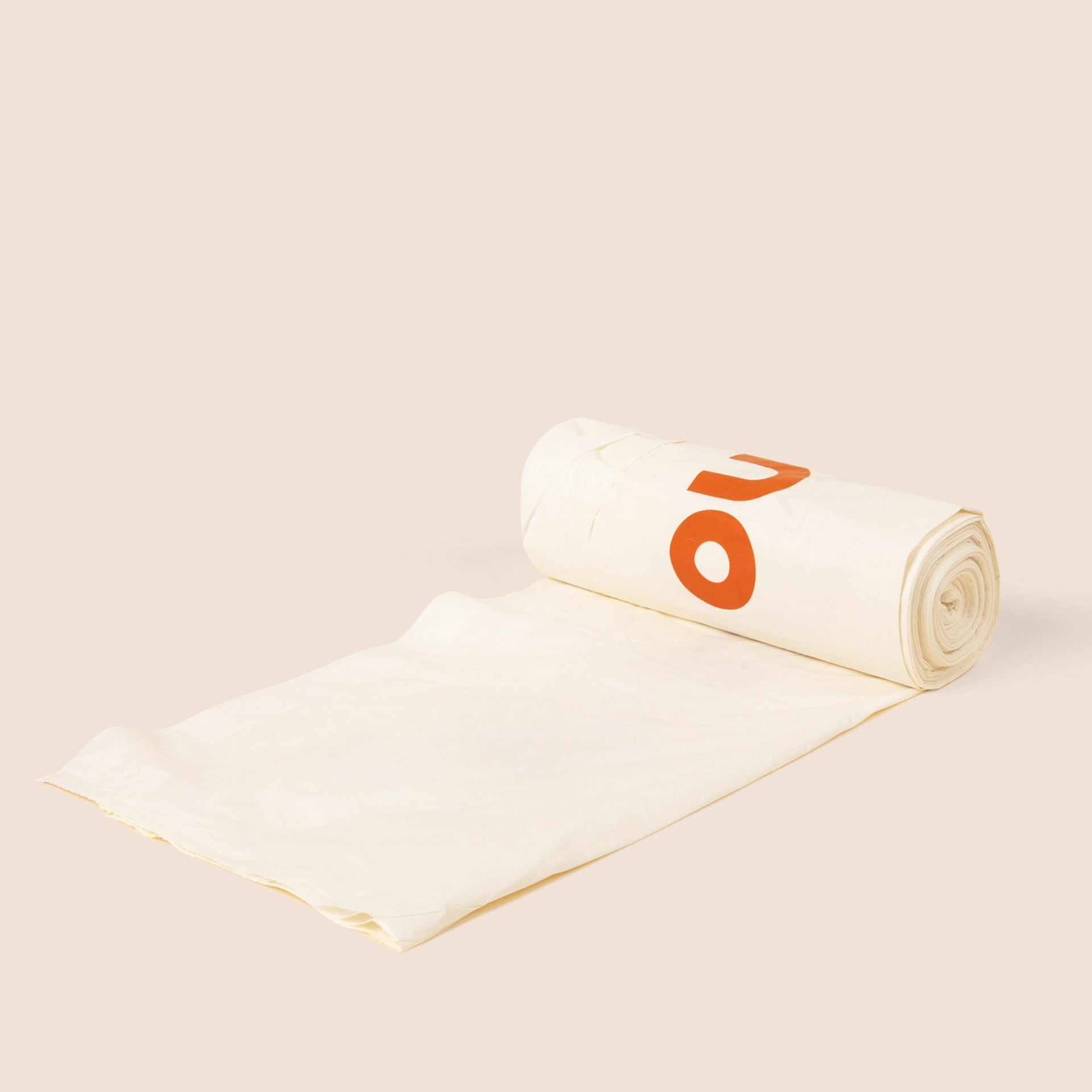 Plastno tall compostable waste bag partially unrolled from its roll, cream-colored with orange Plastno logo