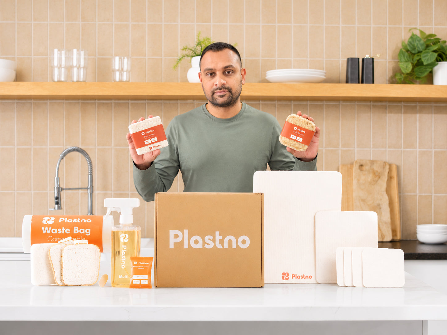 Plastno founder with the full plastic-free cleaning line in a home kitchen, from compostable trash bags and refillable cleaning sprays to biodegradable sponges and reusable cloths.