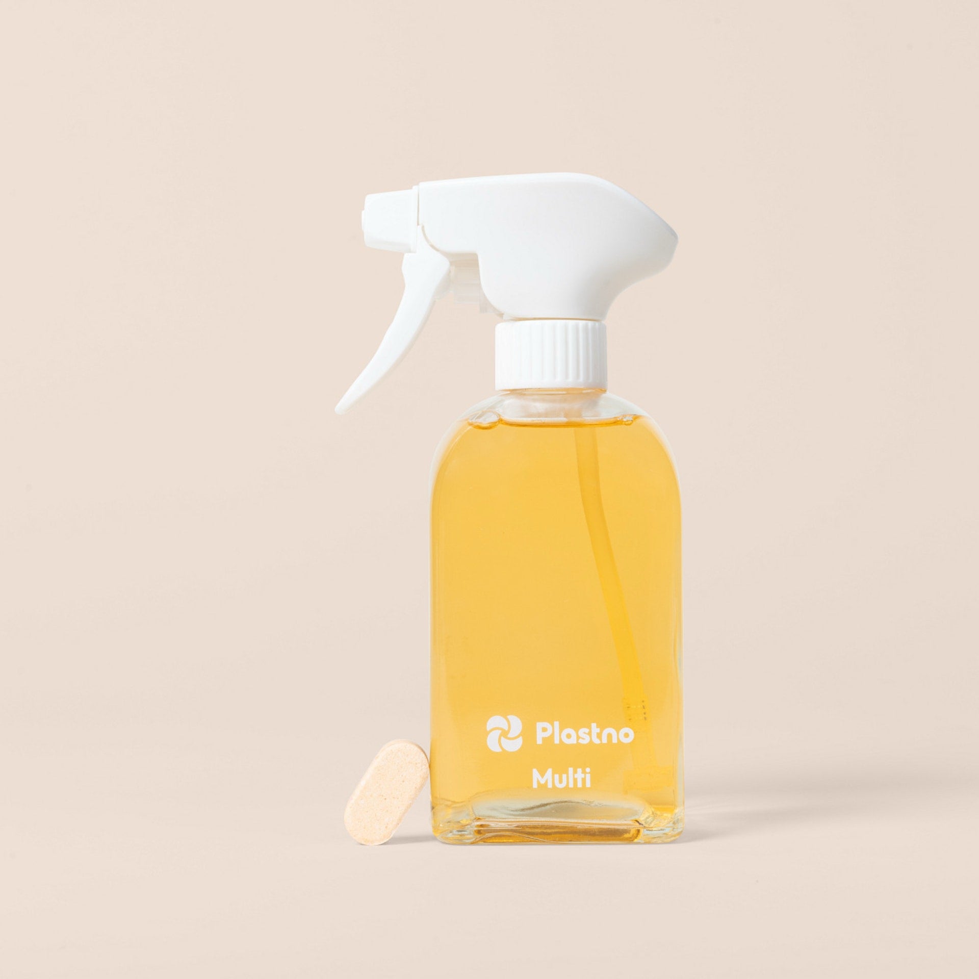 Plastno Multi cleaner glass spray bottle filled with cleaner next to a dissolvable multi cleaner tablet on a beige background