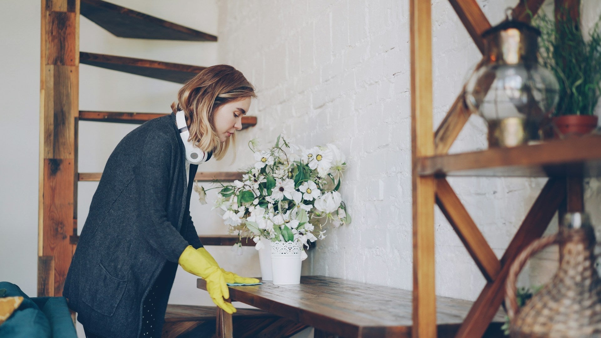 A person wiping a wooden table by hand in a bright home, cleaning without a scented spray