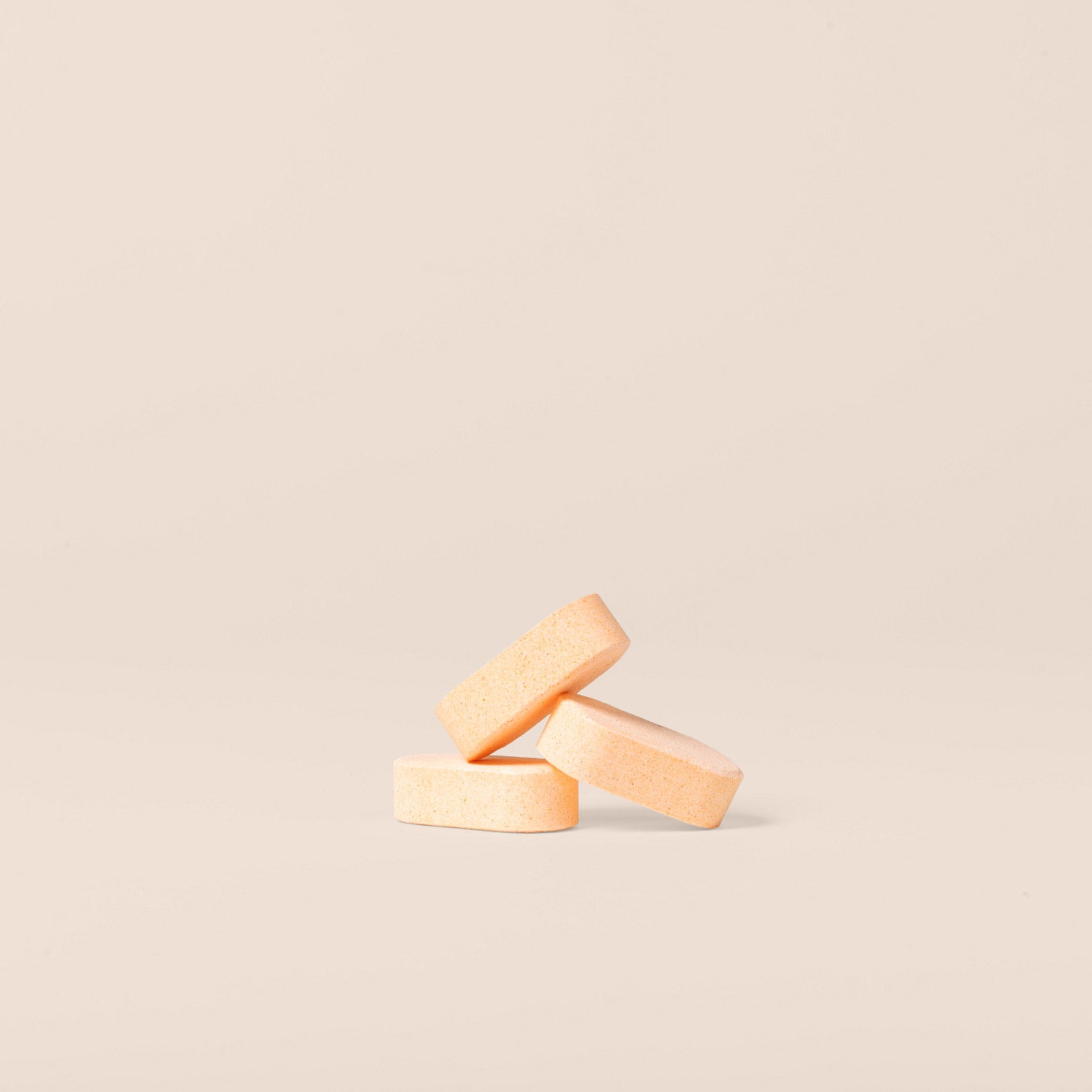 Three Plastno dissolvable multi cleaner tablets stacked on a beige background