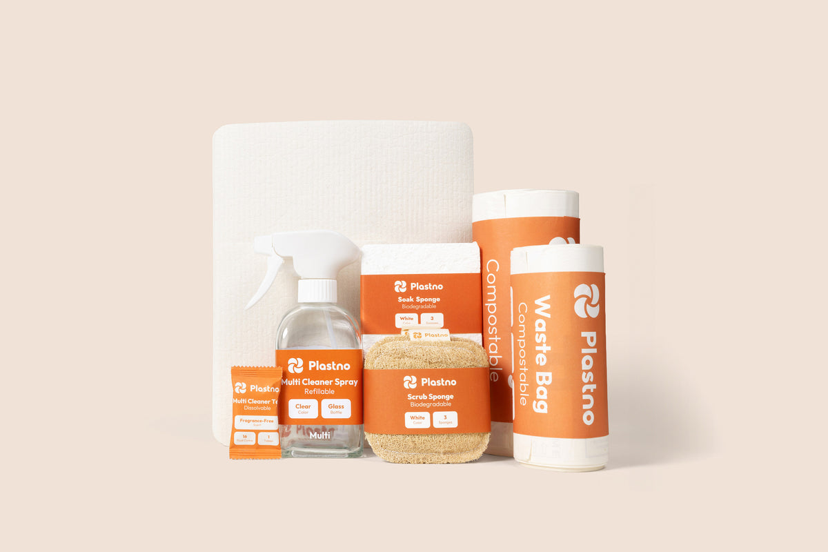 Plastno cleaning bundle centered on a beige background: multi cleaner tablet, refillable glass spray bottle, scrub sponge, soak sponge, sponge towel and two rolls of compostable waste bags