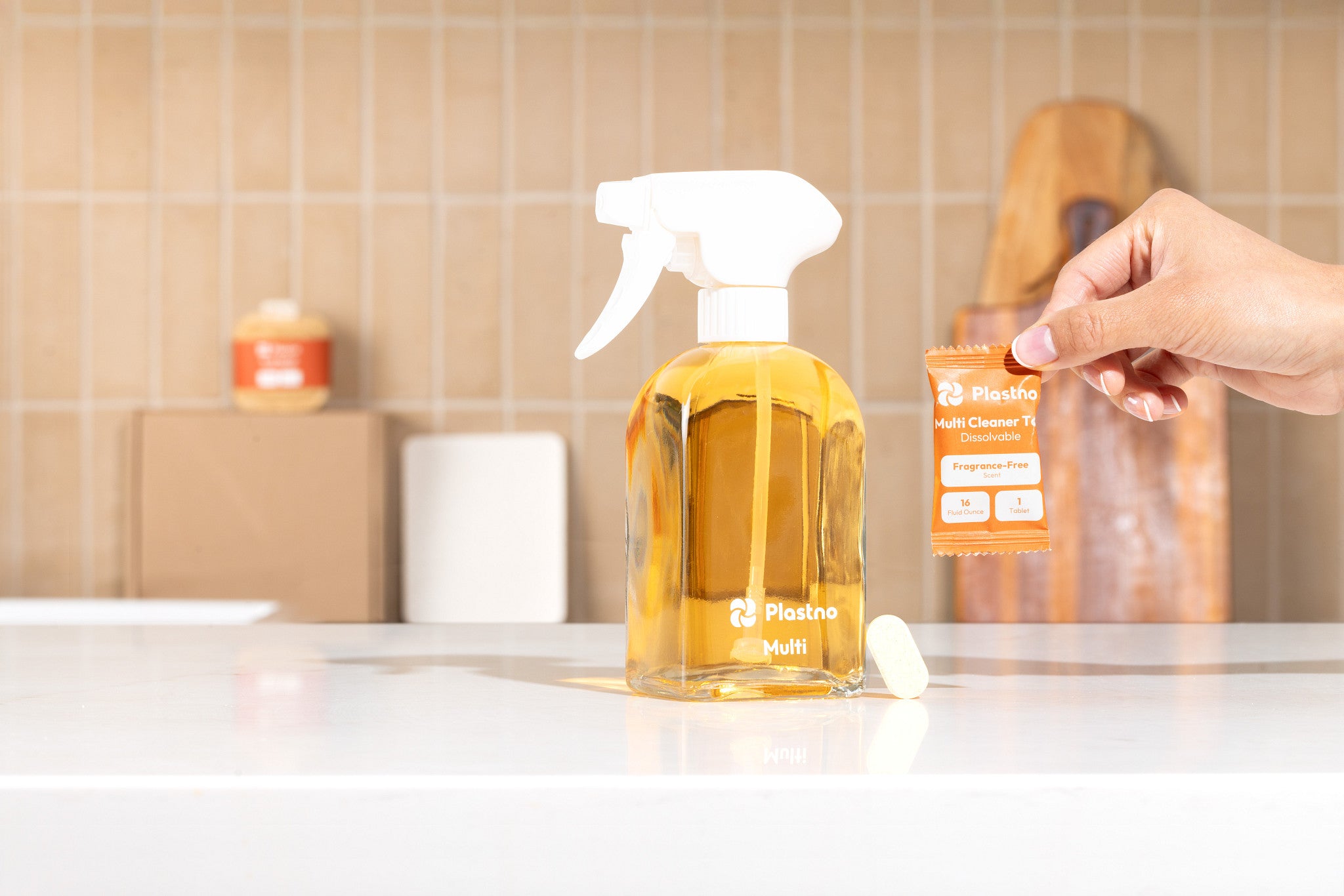 Plastno glass spray bottle filled with Multi cleaner next to a dissolvable multi cleaner tablet and its fragrance-free refill packet