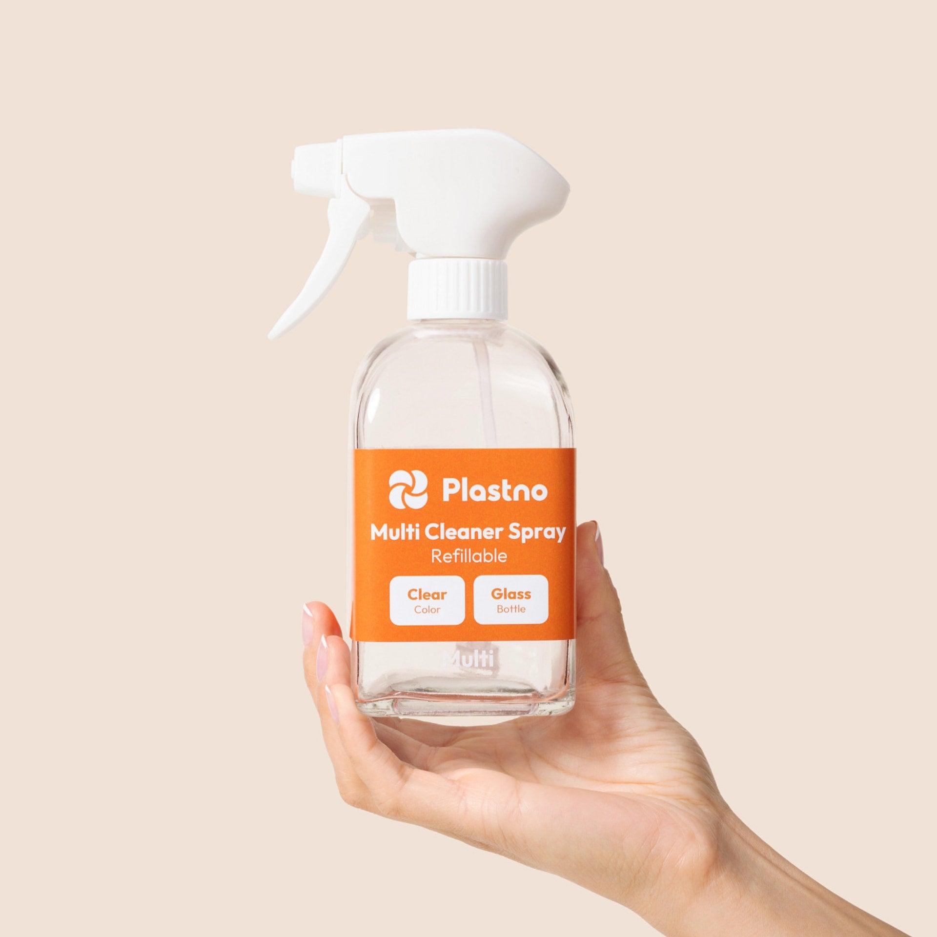 Hand holding the empty Plastno refillable Multi Cleaner Spray glass bottle on a beige background