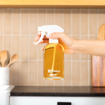Hand holding the Plastno Multi cleaner glass spray bottle filled with cleaner in front of a tiled kitchen backsplash