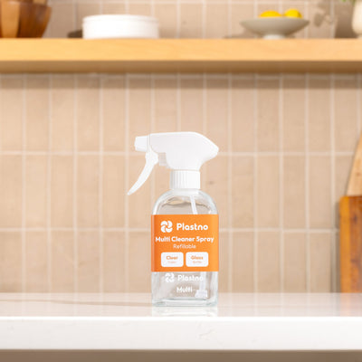 Plastno refillable Multi Cleaner Spray glass bottle with orange label on a kitchen counter in front of a tiled backsplash