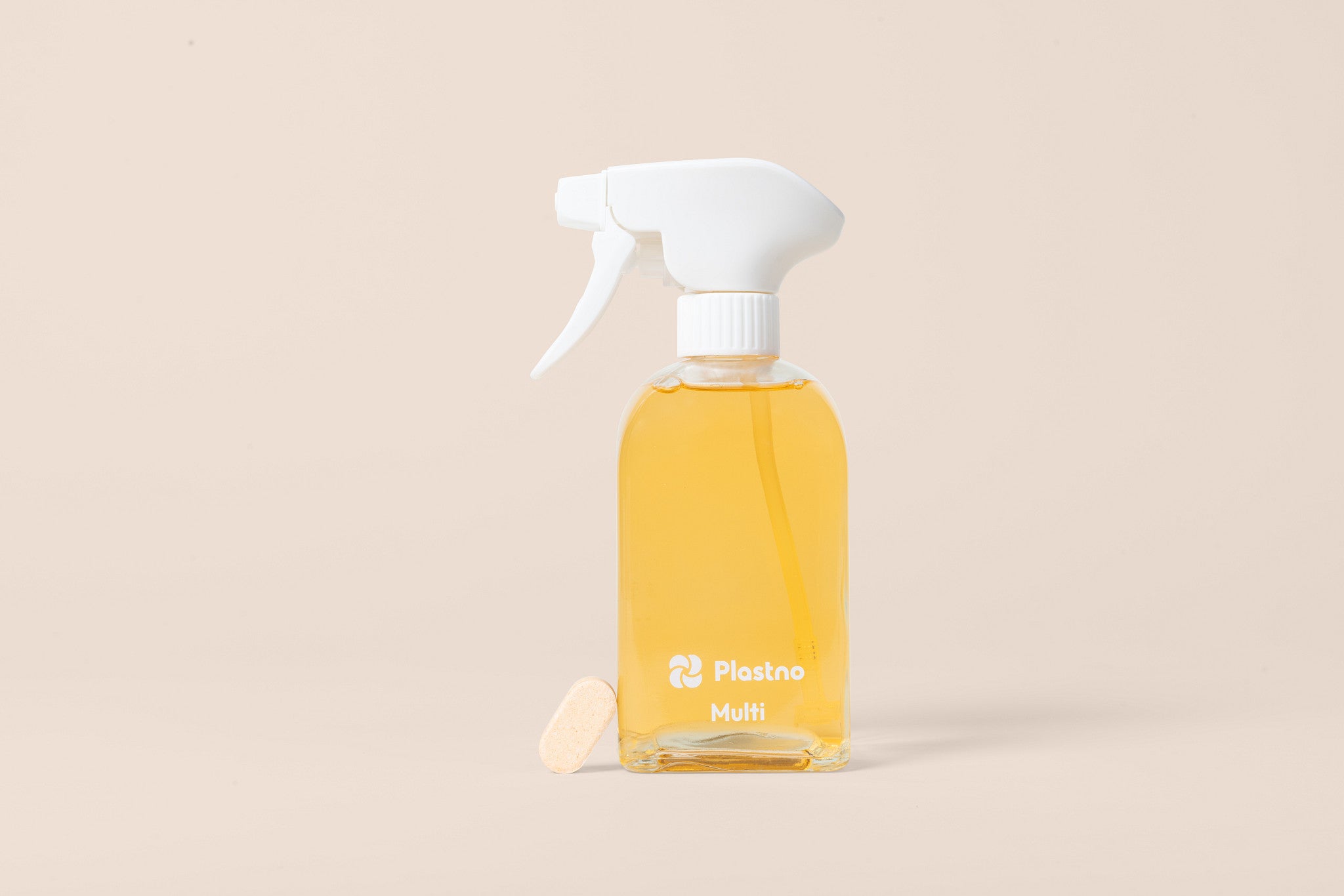 Plastno Multi cleaner glass spray bottle filled with cleaner next to a dissolvable multi cleaner tablet on a beige background