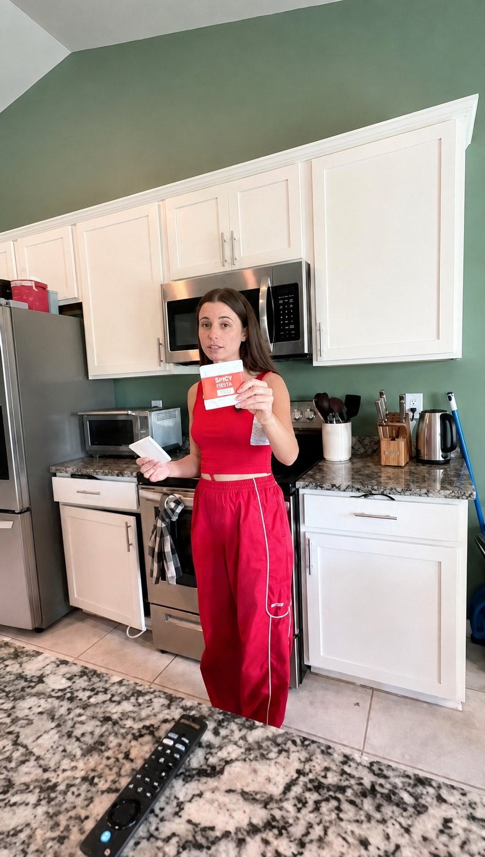 Person holding a white Plastno soak sponge in a kitchen with green walls and white cabinets
