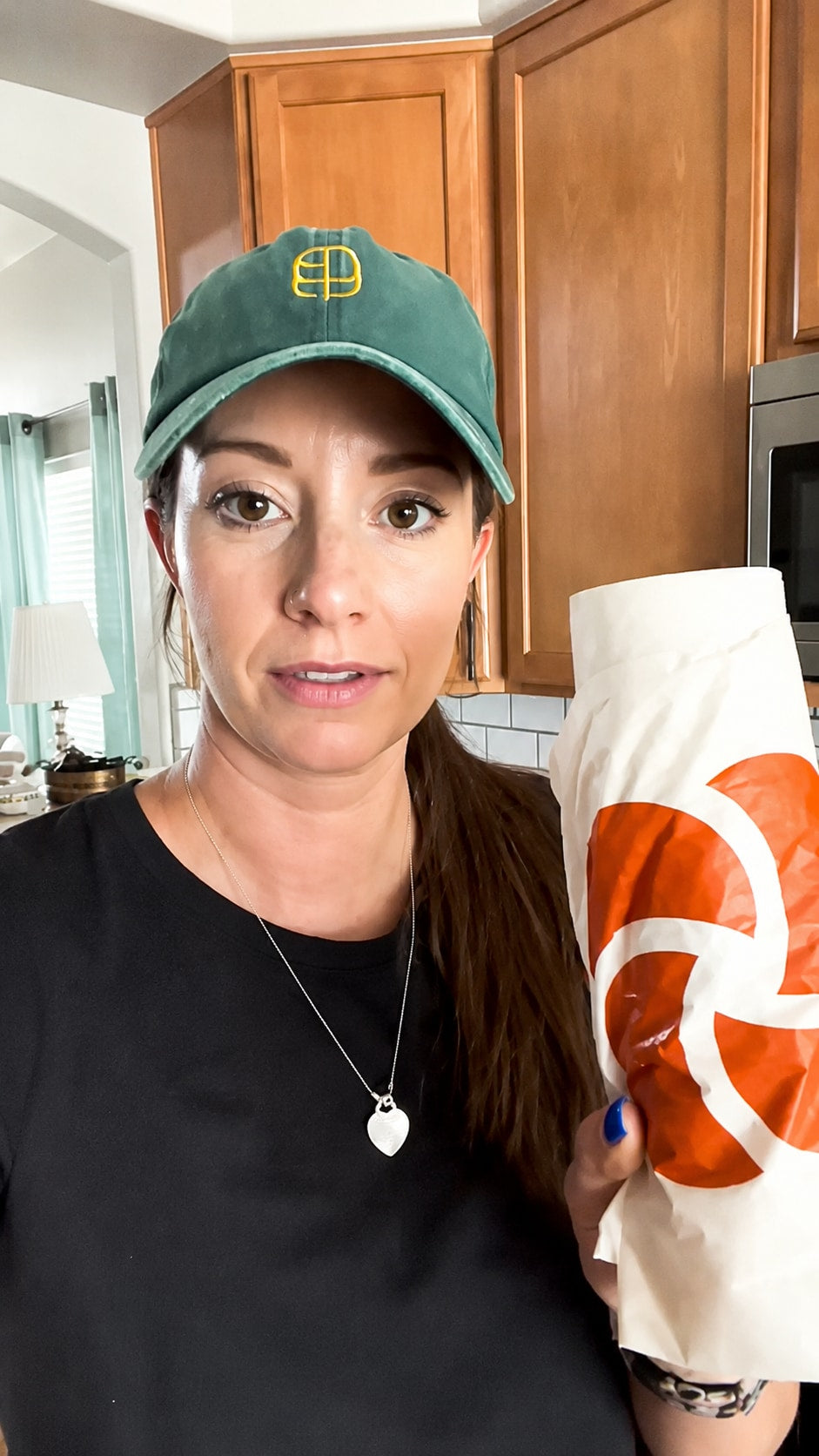 Creator in a kitchen holding a rolled Plastno tall compostable waste bag with the orange logo